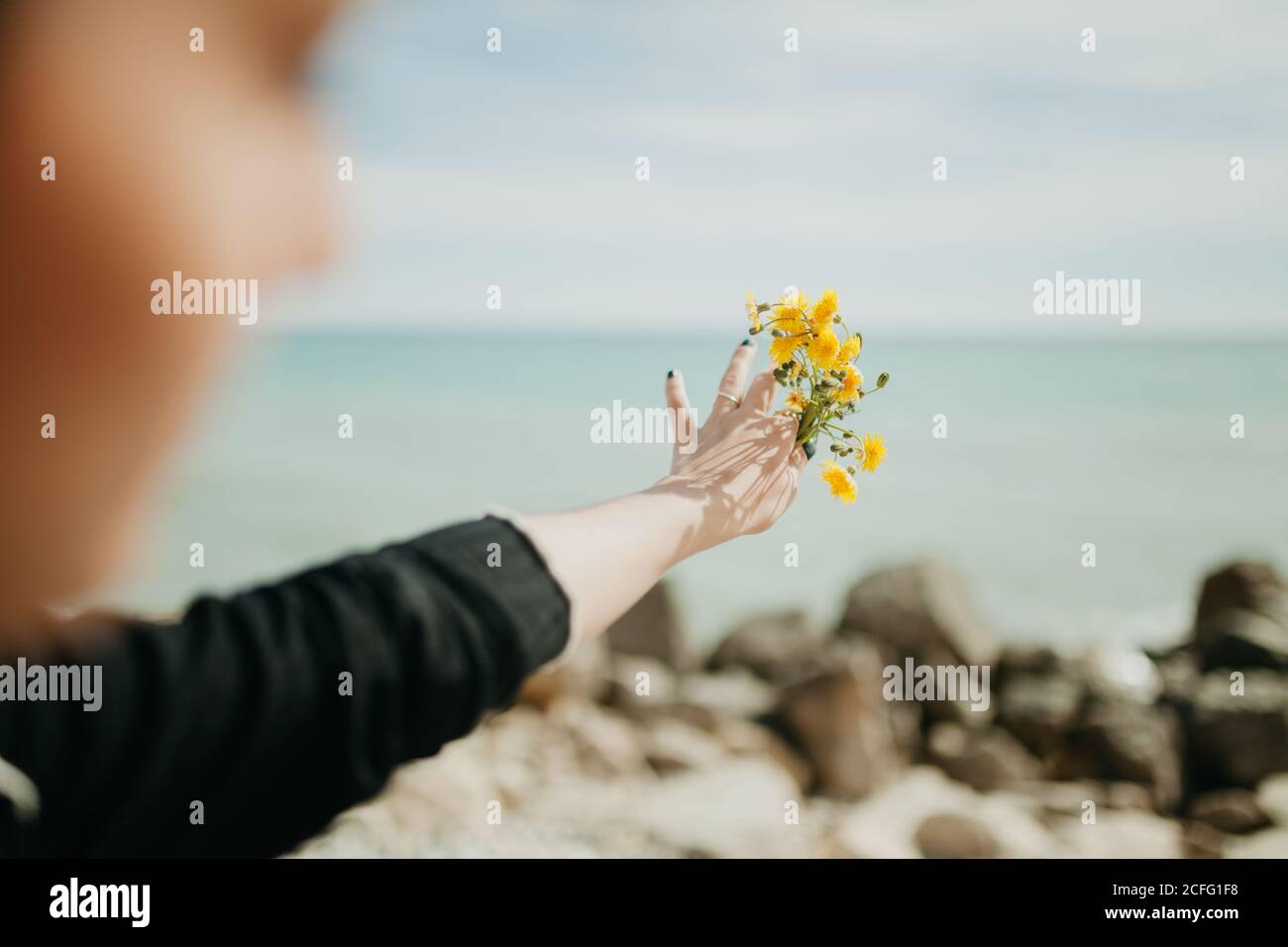 Back view of young Woman throwing small yellow flowers into sea water