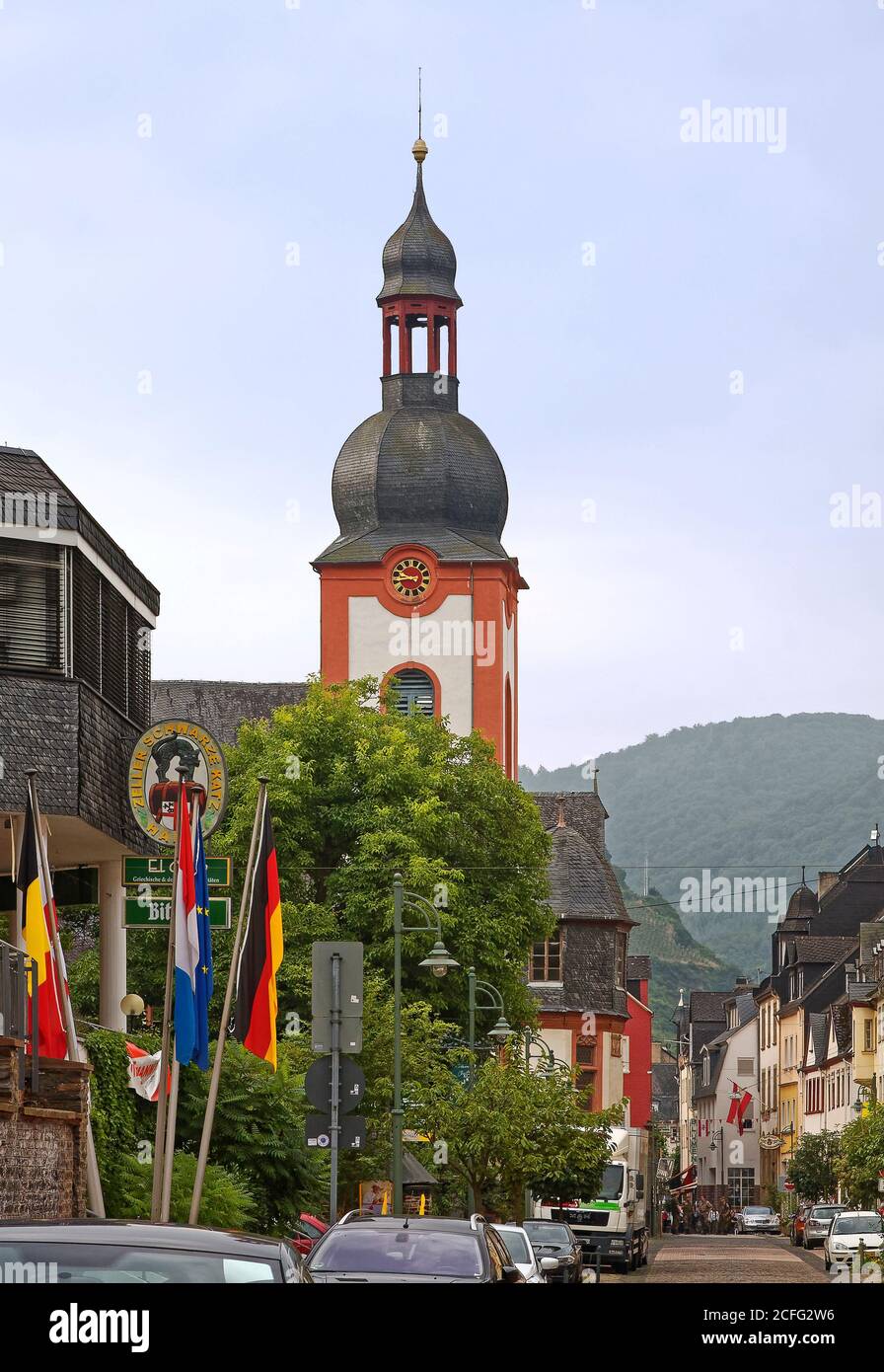 street scene, steeple, clock, St. Peter Church, cityscape, old buildings, flags, vehicles parked, green hillside, Europe, Zell; Germany Stock Photo