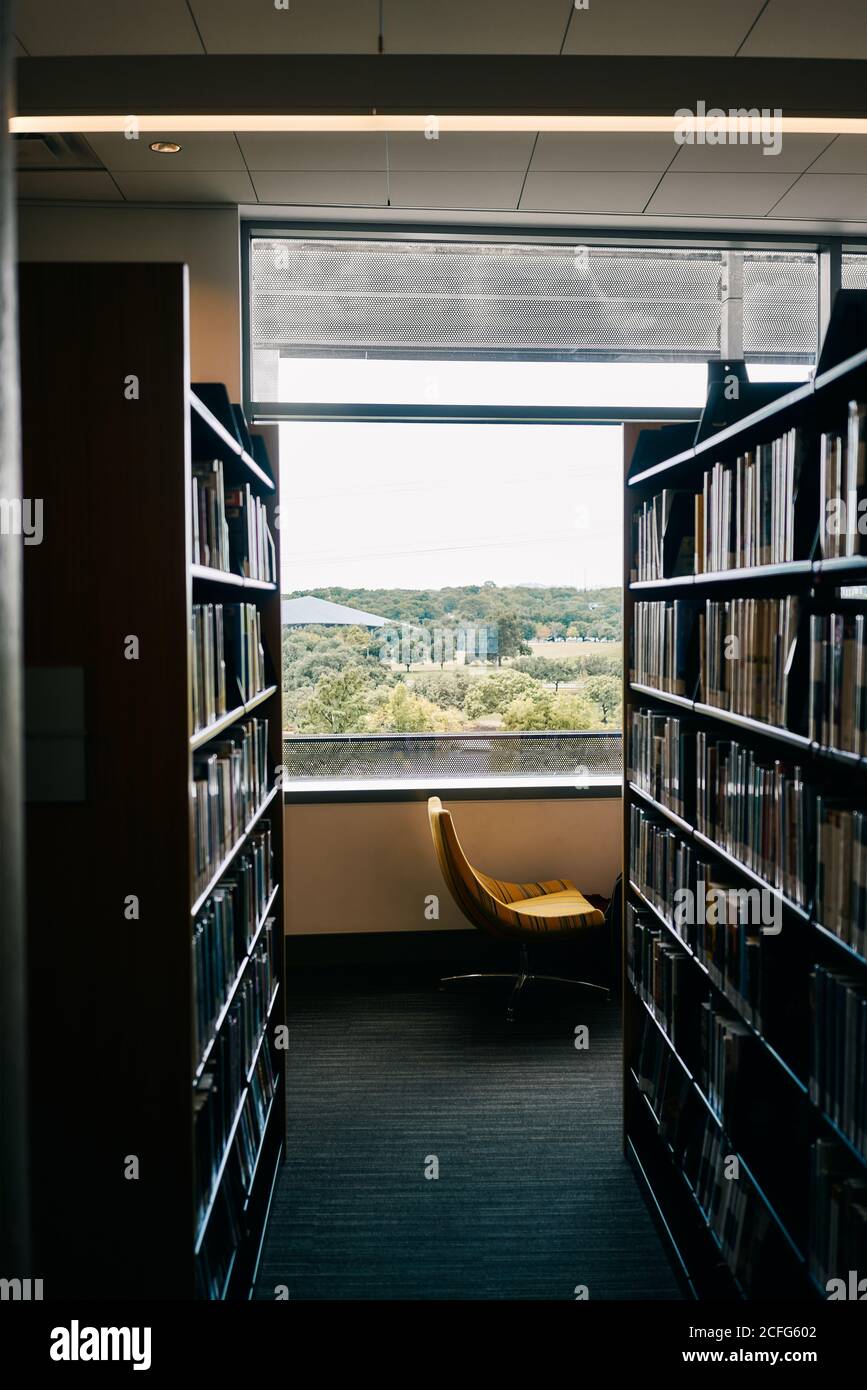 Bookshelves in room with comfortable chair nearby window in library of Texas Stock Photo
