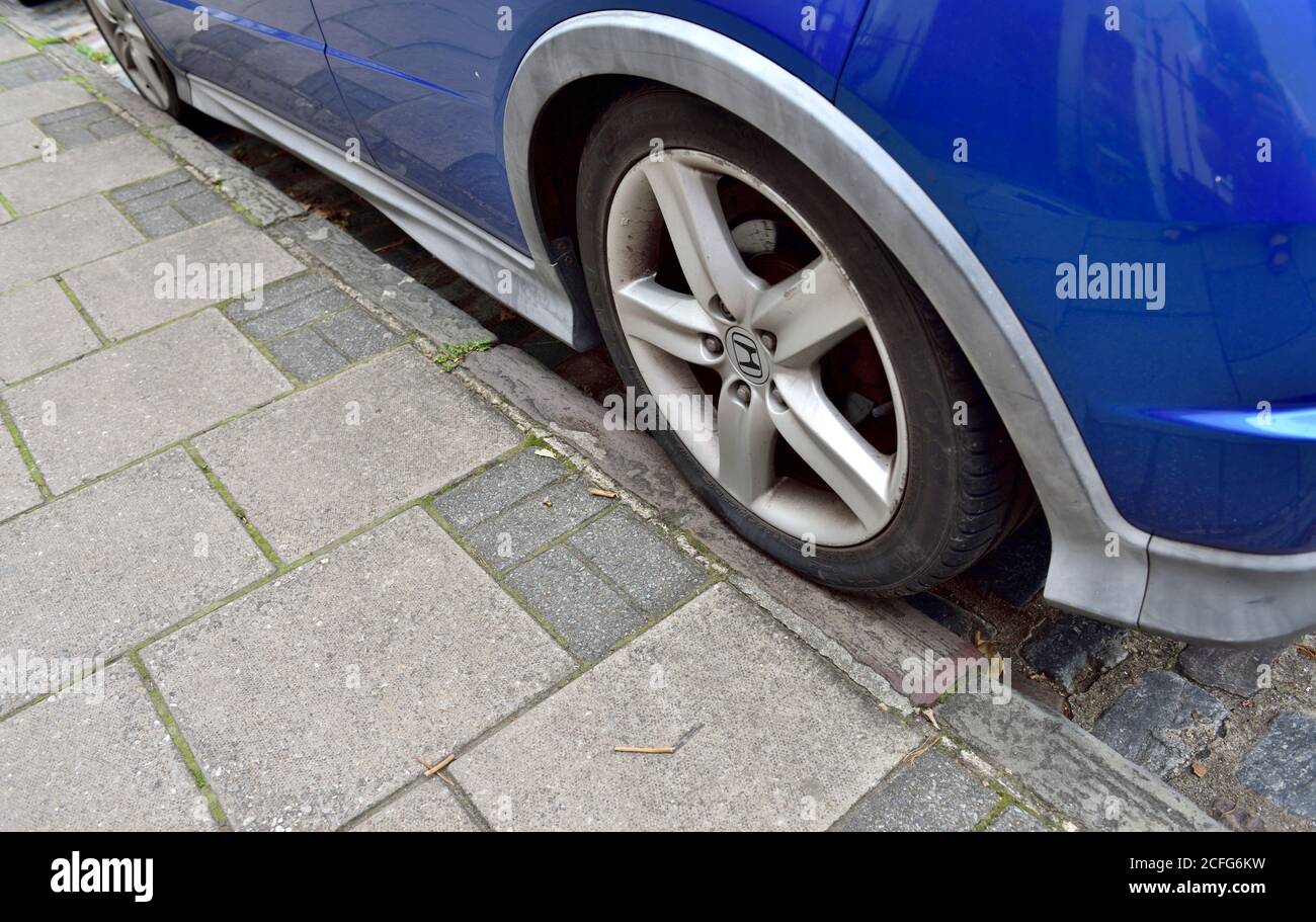 Parked car with single rear wheel accidentally 2 inches onto pavement, illegal in London trying to make illegal in rest of UK with big fines Stock Photo