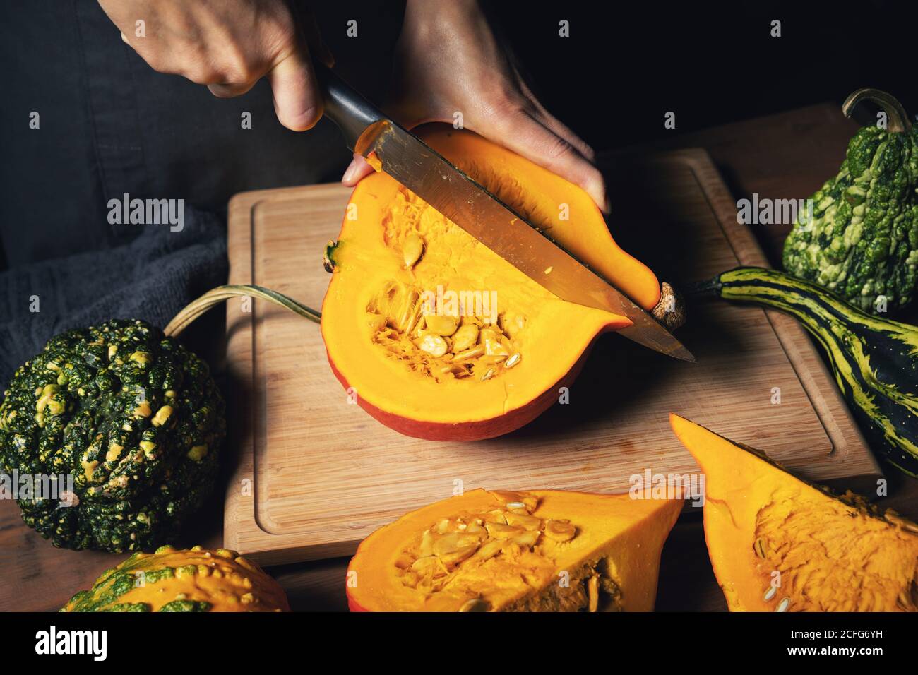 autumn harvest - woman cutting pumpkin for cooking on wooden board Stock Photo