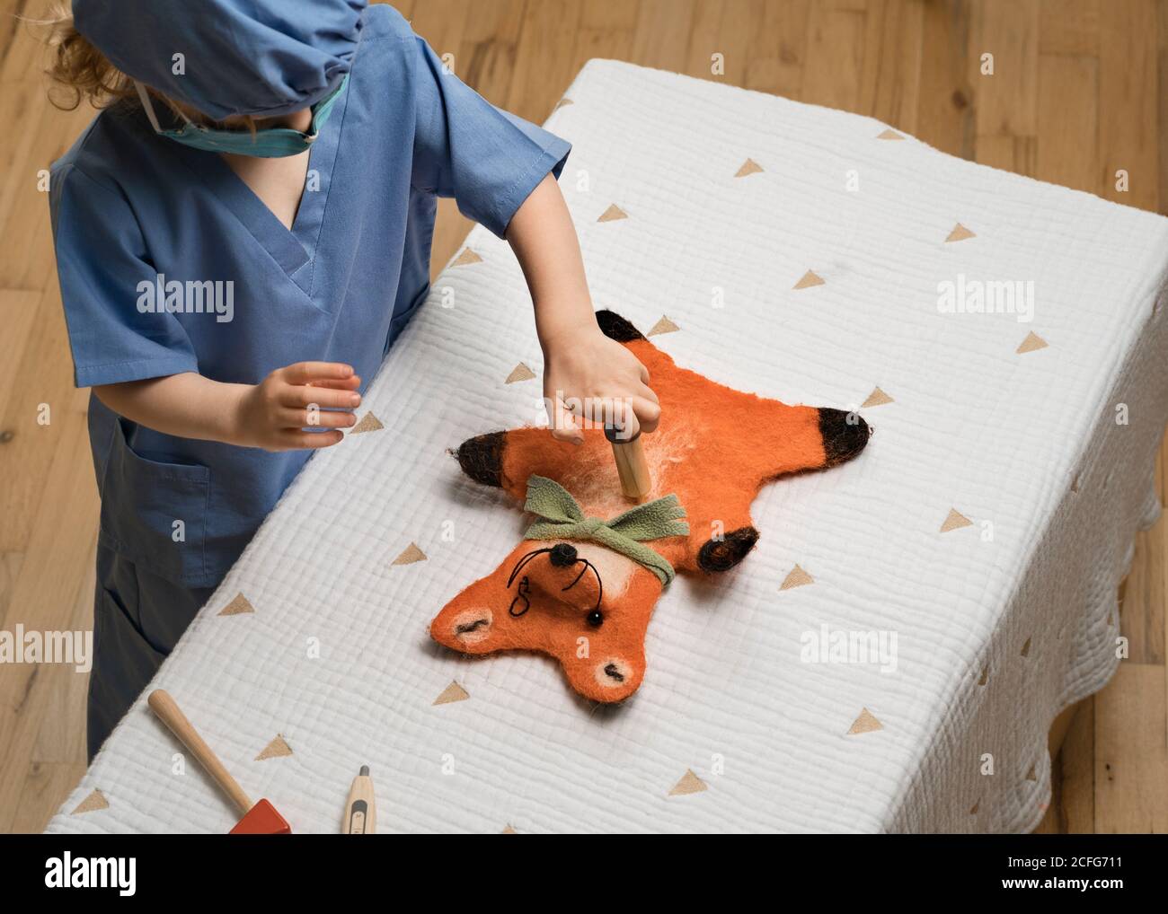 young child wearing medical PPE administers a shot to a plush toy fox hand puppet Stock Photo