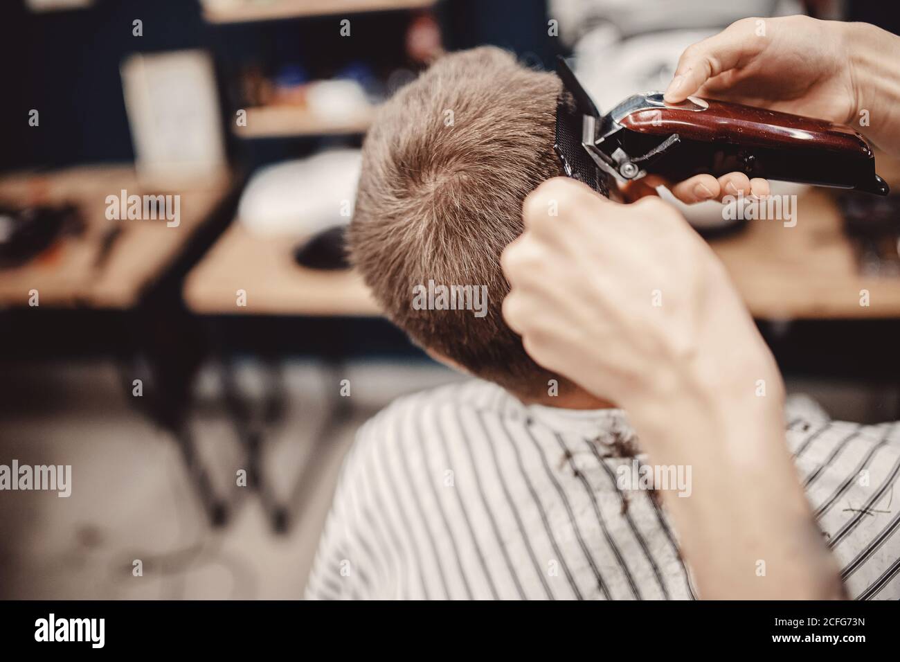 Close-up master Barber does hairstyle and styling hair to guy Stock Photo