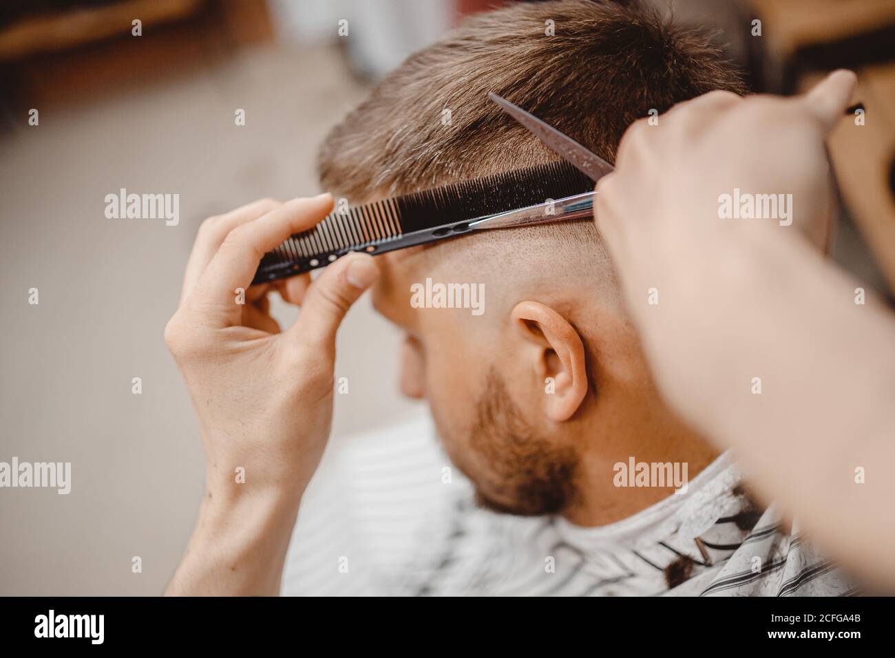 Close-up master Barber does hairstyle and styling hair to guy Stock Photo