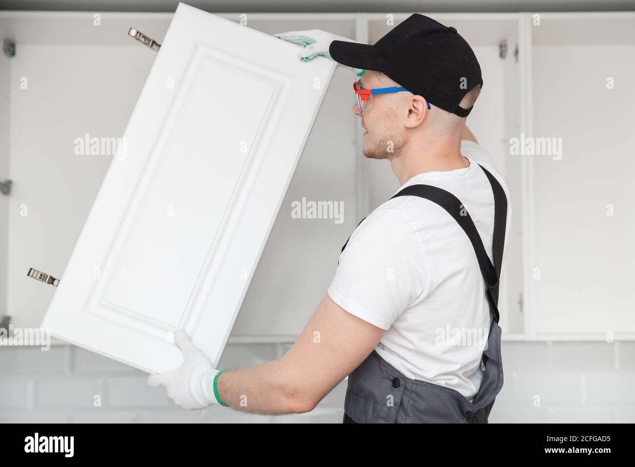 Kitchen installation man. Worker assembling furniture cabinet hinge Stock Photo