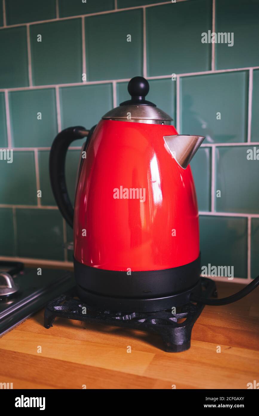 Old-fashioned looking electric kettle in red color on wooden counter in kitchen, Scotland Stock Photo