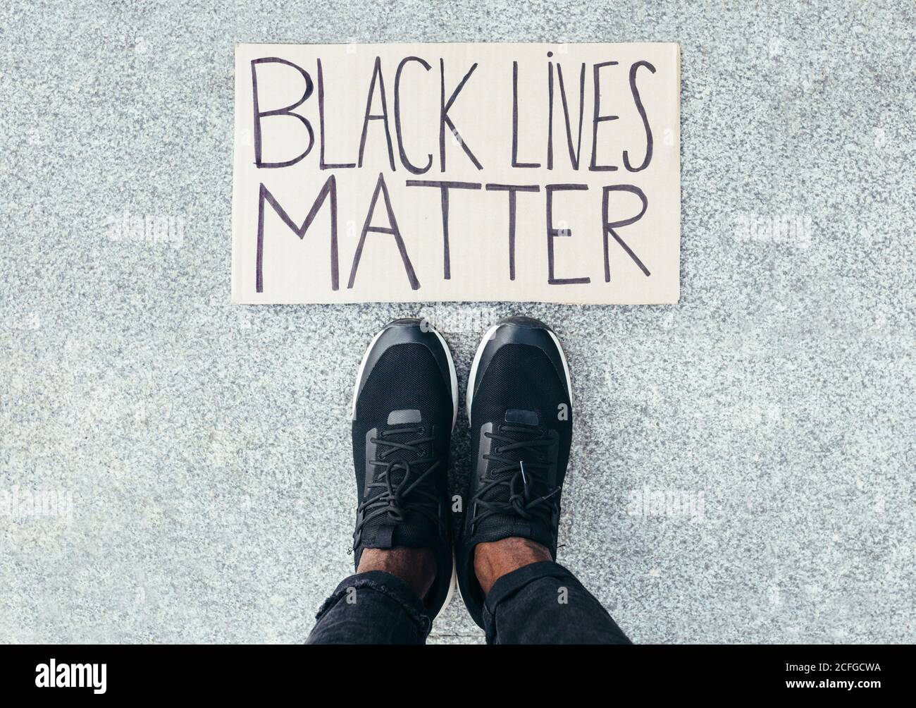 Feet detail besides a Black Lives Matter sign on floor. A a gesture against racism Stock Photo