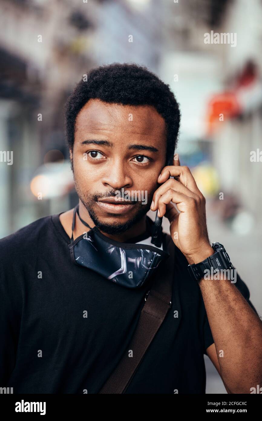 Black man talking on cellphone with serious expression in the street Stock Photo