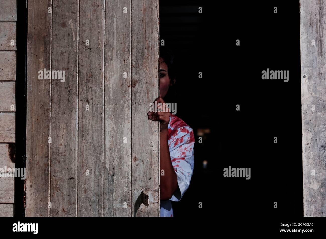 Woman stand behind the door with blood at wood house, Halloween concept. Stock Photo