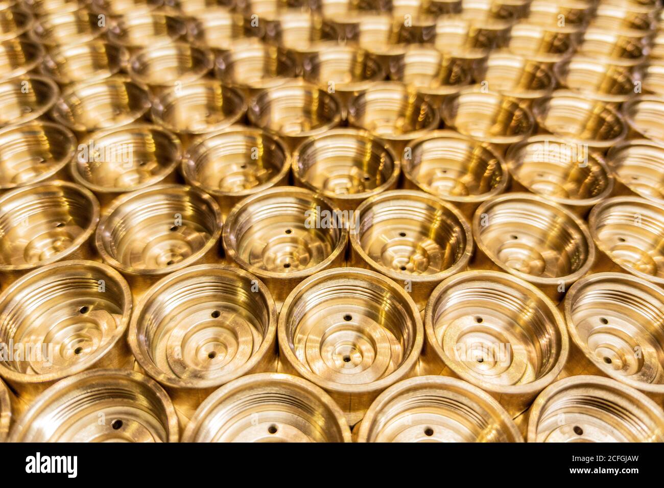 an abstract perspective industrial close-up background of shiny brass metal threaded hexagonal fitting parts Stock Photo