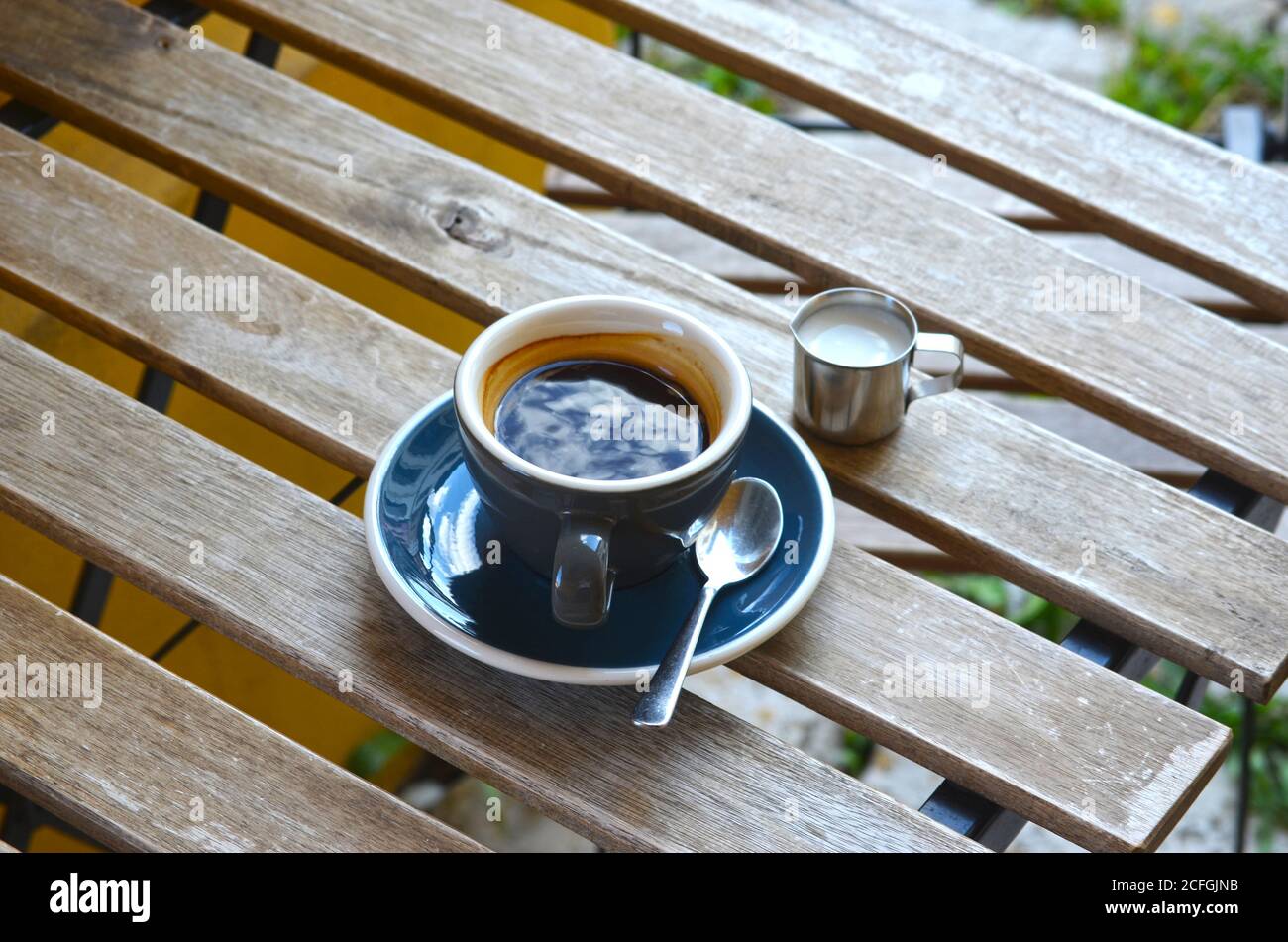 https://c8.alamy.com/comp/2CFGJNB/espresso-lungo-coffee-in-a-blue-cup-with-milk-in-a-little-metal-jug-on-a-wooden-table-2CFGJNB.jpg