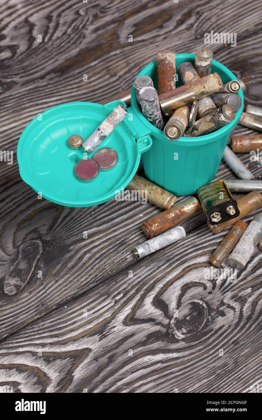 Corroded used batteries. They lie in and around the trash can. Disposal