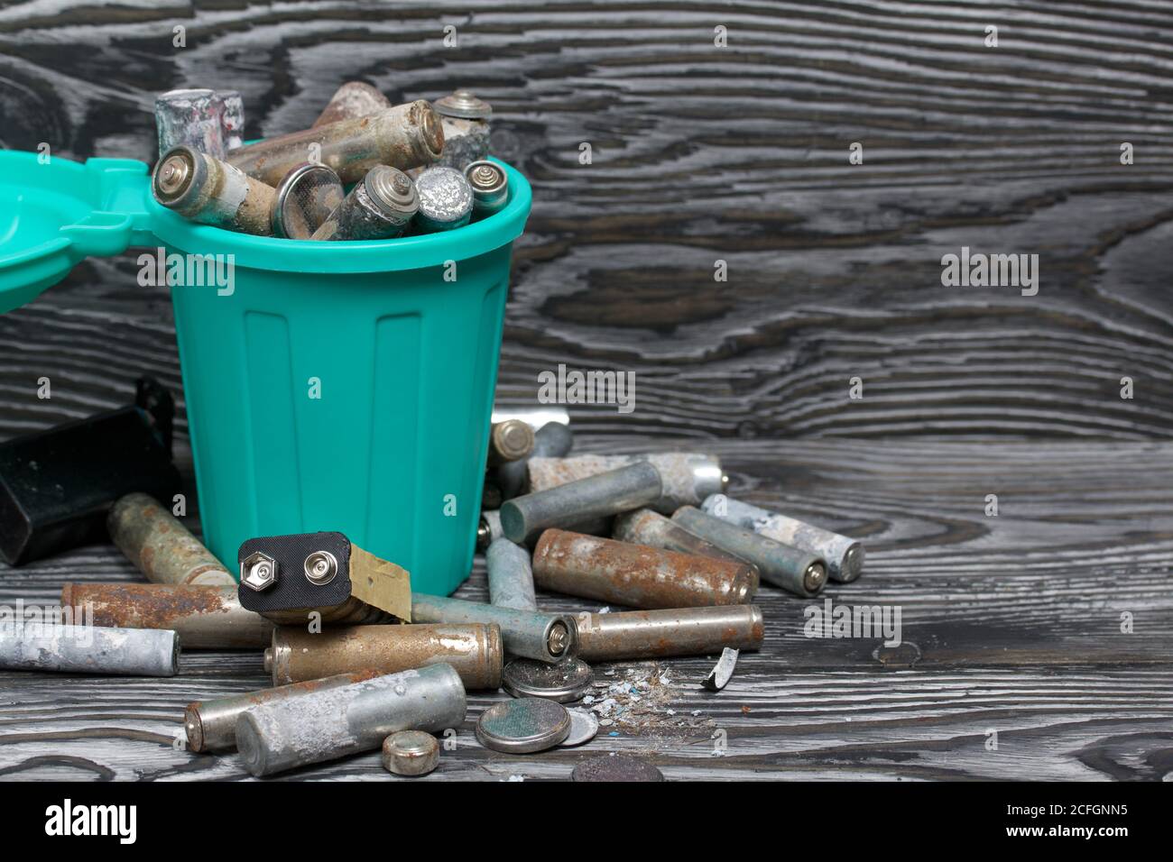 Corroded used batteries. They lie in and around the trash can. Disposal