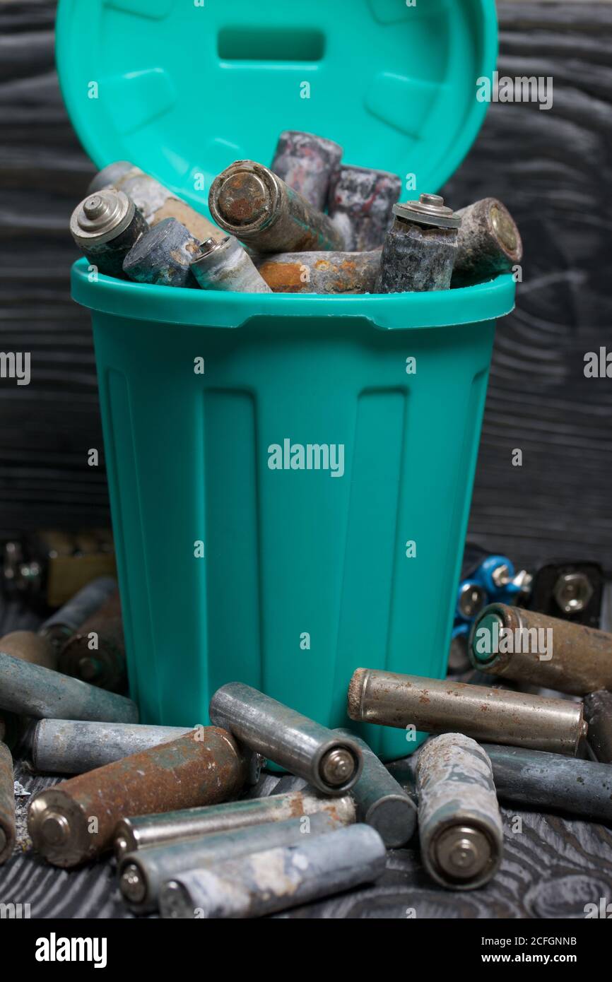Corroded used batteries. They lie in and around the trash can. Disposal