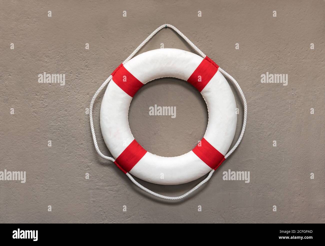 Circular red and white life preserver or lifebuoy hanging on a wall for use as a buoyancy aid or flotation device in case of drowning or sinking of a Stock Photo