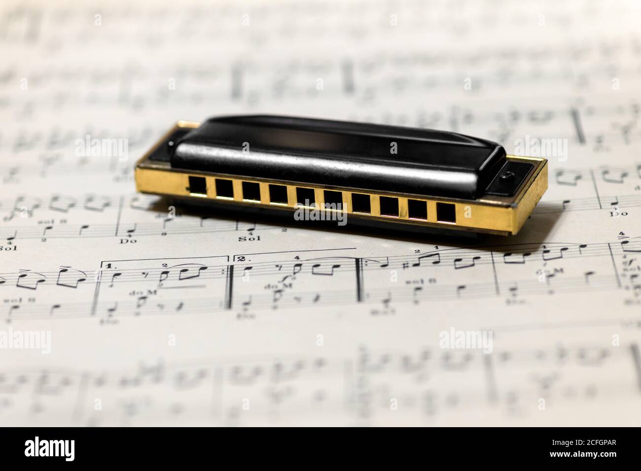 Mouth organ or harmonica on a music score or sheet music with selective focus to the musical instrument and copyspace Stock Photo
