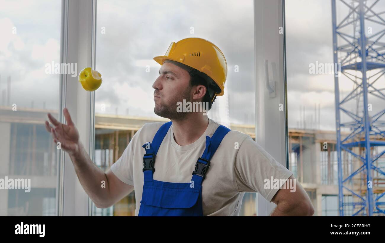 Comic fail. Builder drops the apple and pics it up. Stock Photo