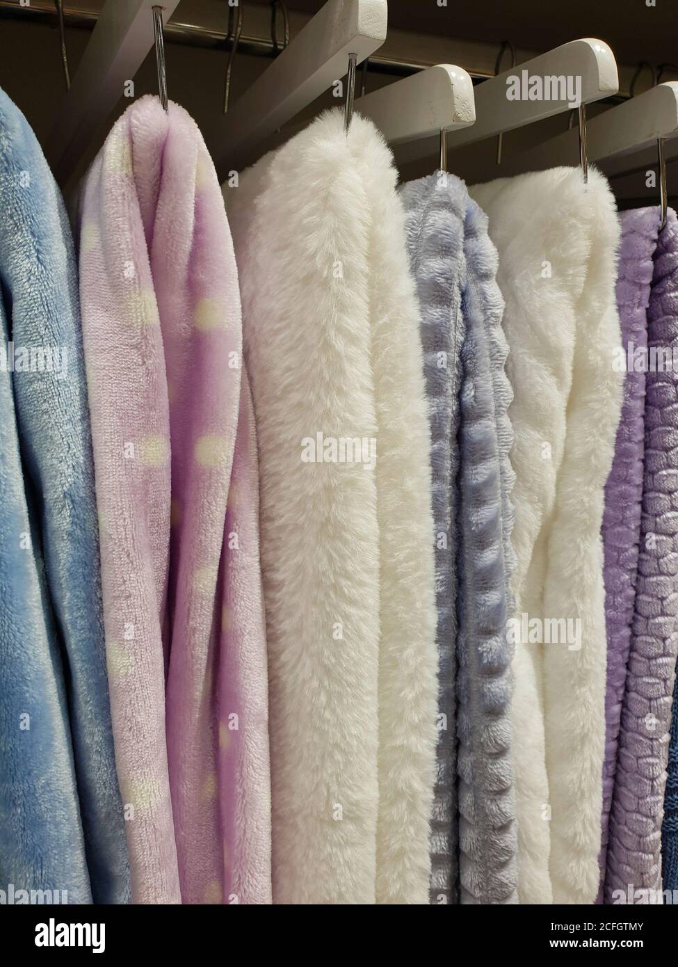 Blankets of different colors are hanging on the shop window Stock Photo