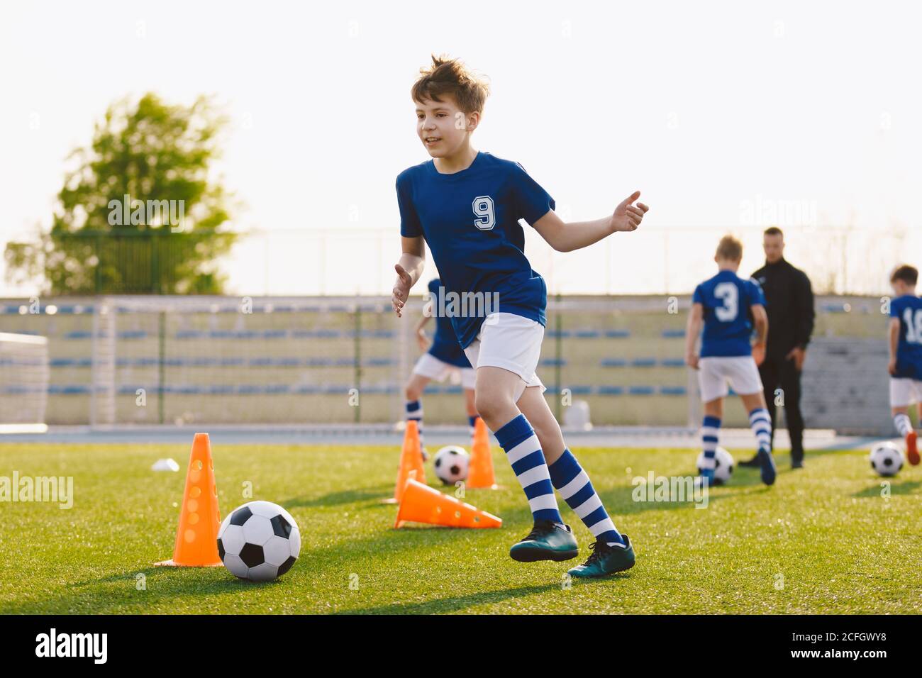 Boys running after ball on soccer training unit. Children having fun on football practice session. School physical education class on summer day Stock Photo