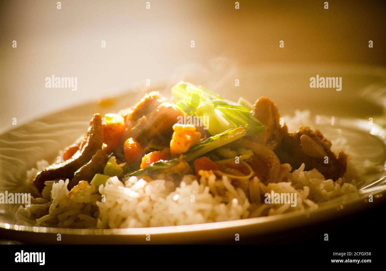 Asian stir fry and rice on plate steaming hot Stock Photo