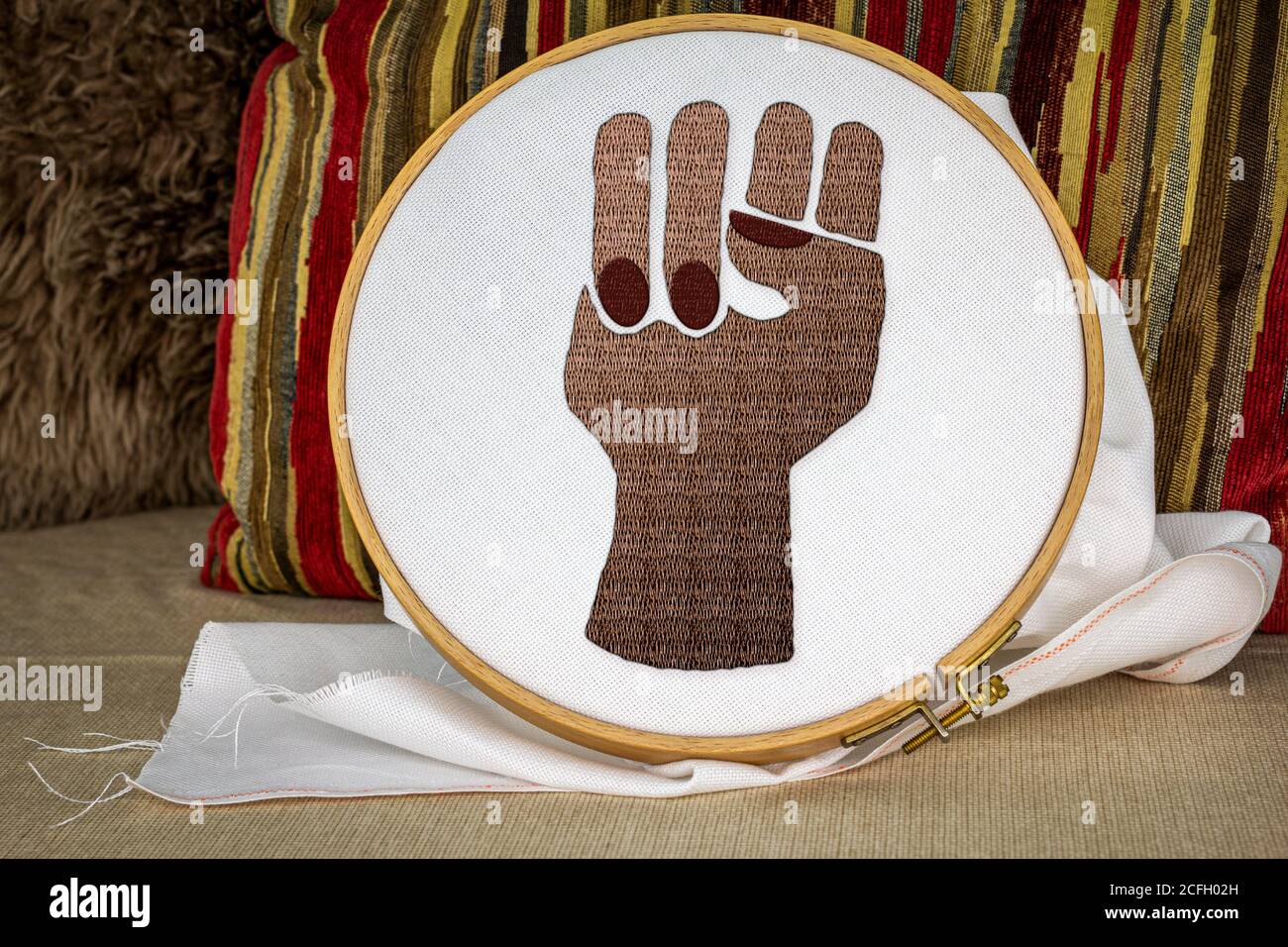 Black embroidered raised power fist on sewing hoop, activism through craft, craftivism, black lives matter, feminism, senior women joining in protests Stock Photo