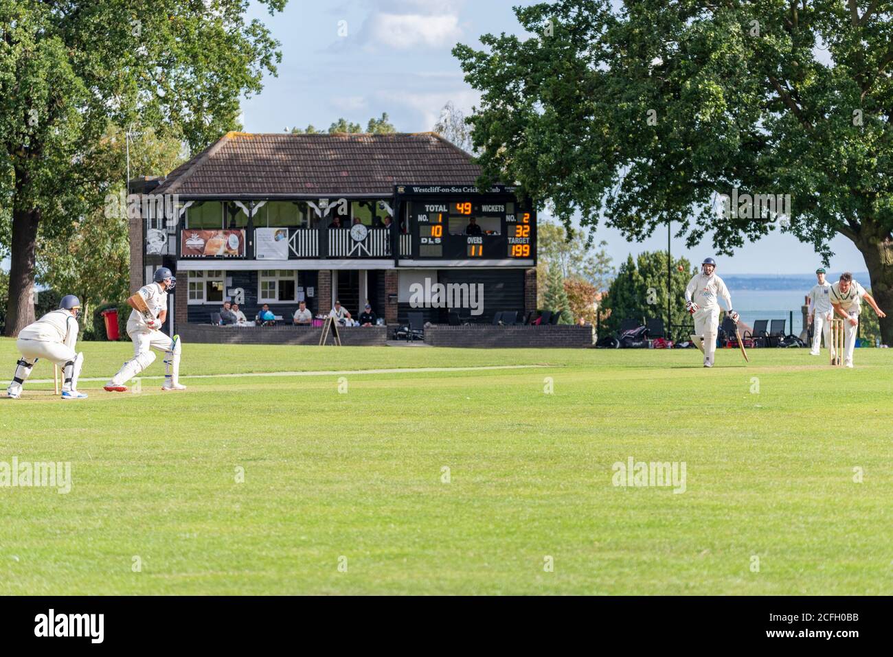 Cricket being played in Chalkwell Park, Westcliff on Sea, Southend, Essex, UK. Westcliff on Sea Cricket Club playing Southend. Clubhouse and estuary Stock Photo