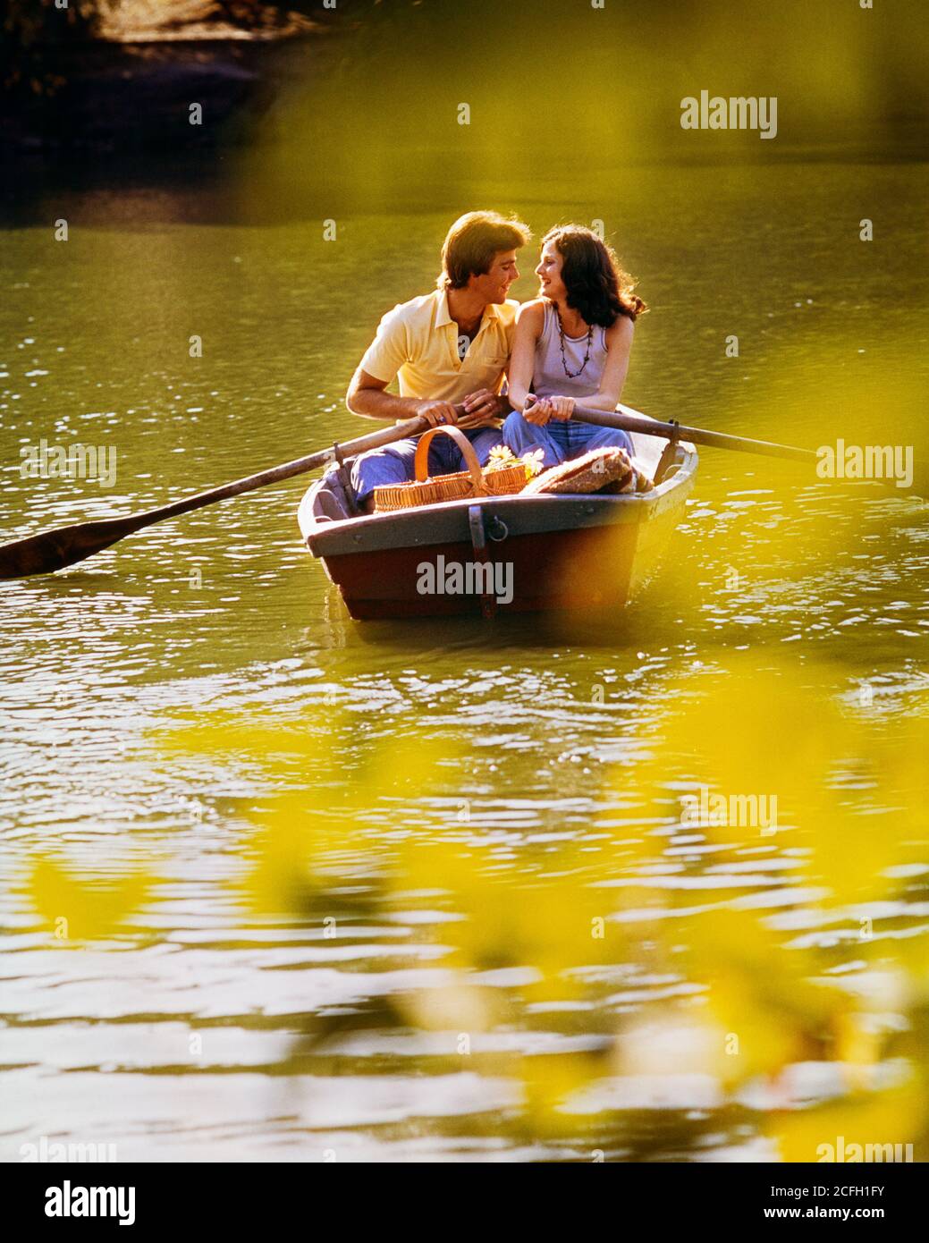 1970s ROMANTIC COUPLE MAN WOMAN SIDE-BY-SIDE IN ROWBOAT WITH PICNIC BASKET SOFT FOCUS GRAPHIC EFFECT CENTRAL PARK NYC USA - kb10981 PHT001 HARS SOFT SILLY COMMUNICATION YOUNG ADULT COMIC SEXY TEAMWORK STRONG CENTRAL JOY LIFESTYLE FEMALES MARRIED RURAL SPOUSE HUSBANDS HEALTHINESS UNITED STATES COPY SPACE FRIENDSHIP HALF-LENGTH LADIES PERSONS UNITED STATES OF AMERICA CARING MALES FOCUS PARTNER DATING DREAMS HUMOROUS HAPPINESS EXCITEMENT RECREATION COMICAL ATTRACTION NYC RELATIONSHIPS ROWBOAT COURTSHIP CONCEPTUAL NEW YORK CITIES COMEDY NEW YORK CITY PERSONAL ATTACHMENT POSSIBILITY AFFECTION Stock Photo