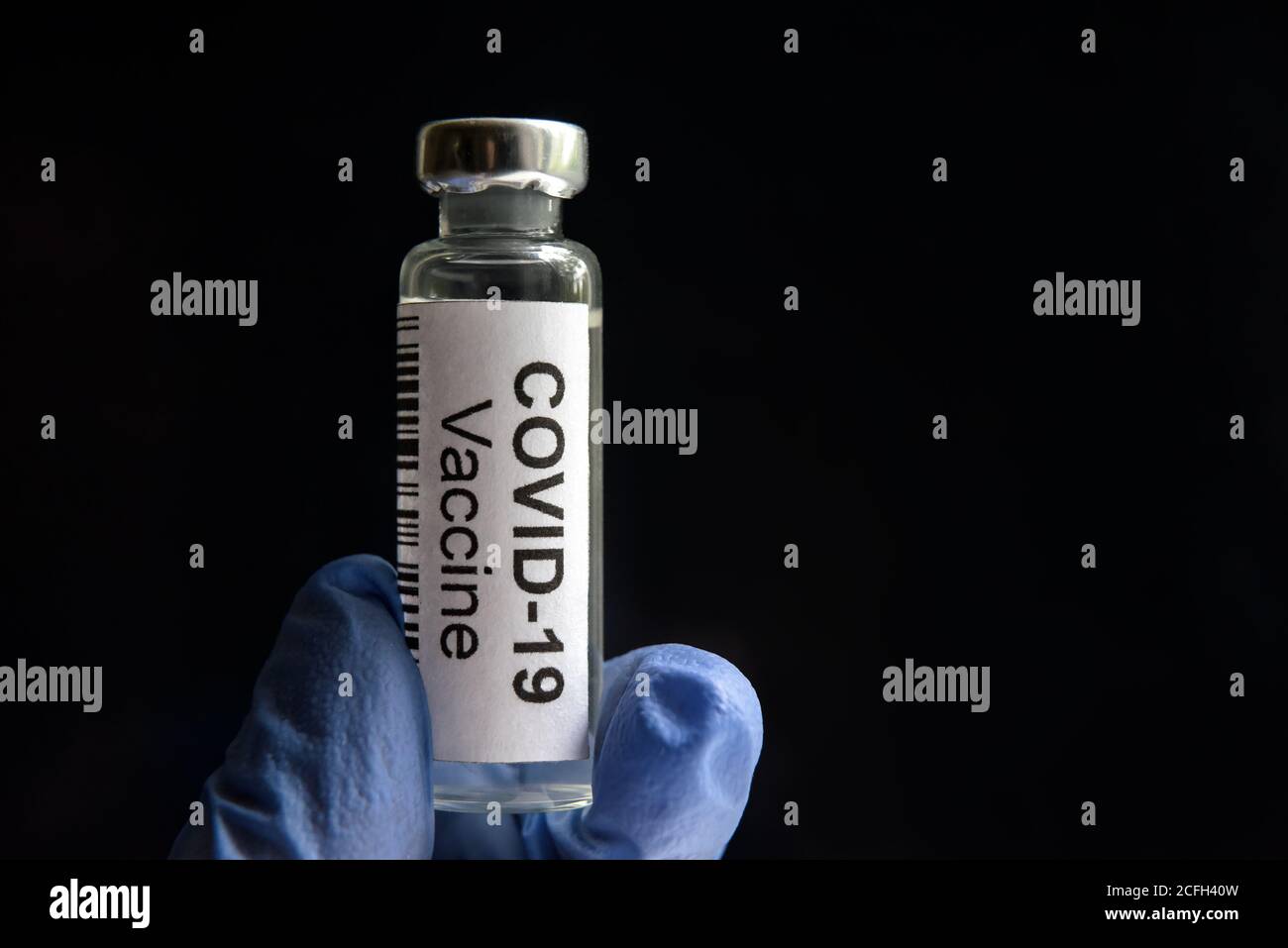 COVID-19 vaccine on black background, medication bottle for SARS-CoV-2 corona virus cure. Modern coronavirus drug in hands close-up. Concept of medici Stock Photo