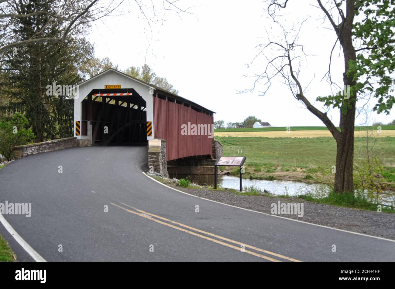 View of road leading up to Erb's Mill covered bridge, over Hammer Creek, in the springtime Stock Photo