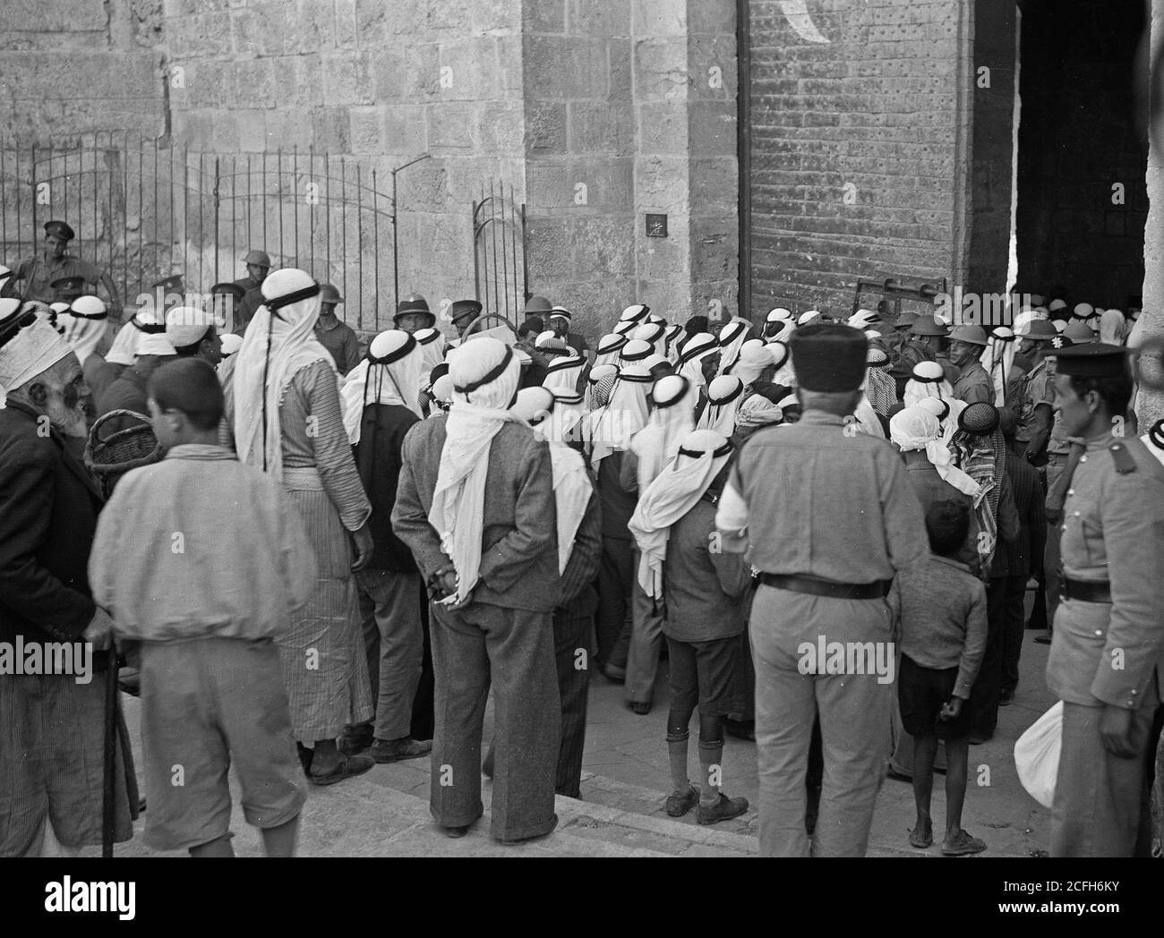 Middle East History - The raising of the siege of Jerusalem. Arab crowds entering the Damascus Gate passing British guard with steel helmets & drawn bayonets Stock Photo