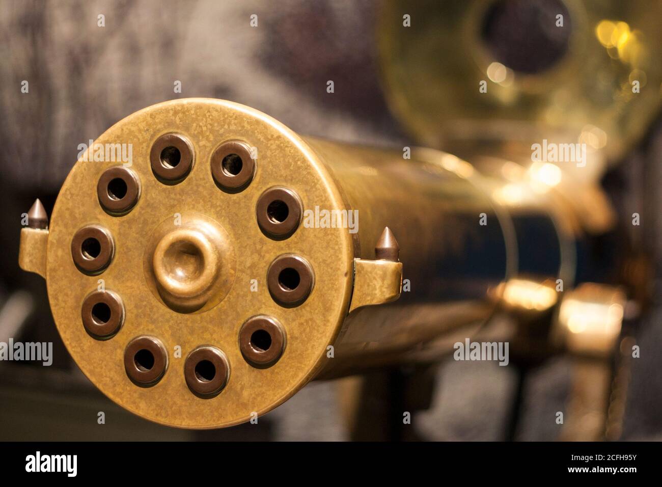 Gatling Gun Muzzle: The muzzle of a brass ten chamber rotating barrel gun used during the first world war. A large sight is in the background. Stock Photo