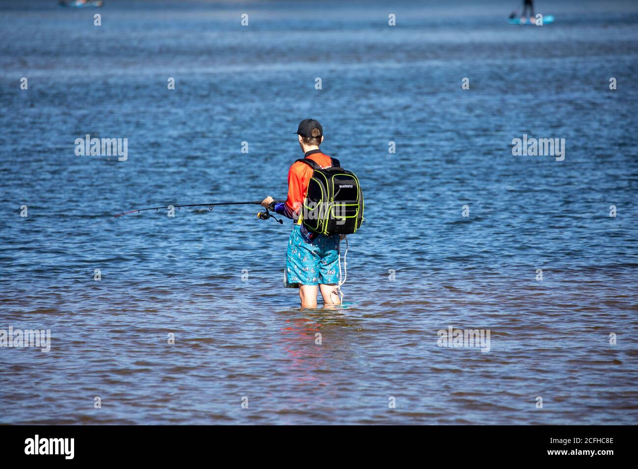 Australian male stood knee high in a Sydney lake holding a fishing rod and fishing,Sydney,Australia Stock Photo