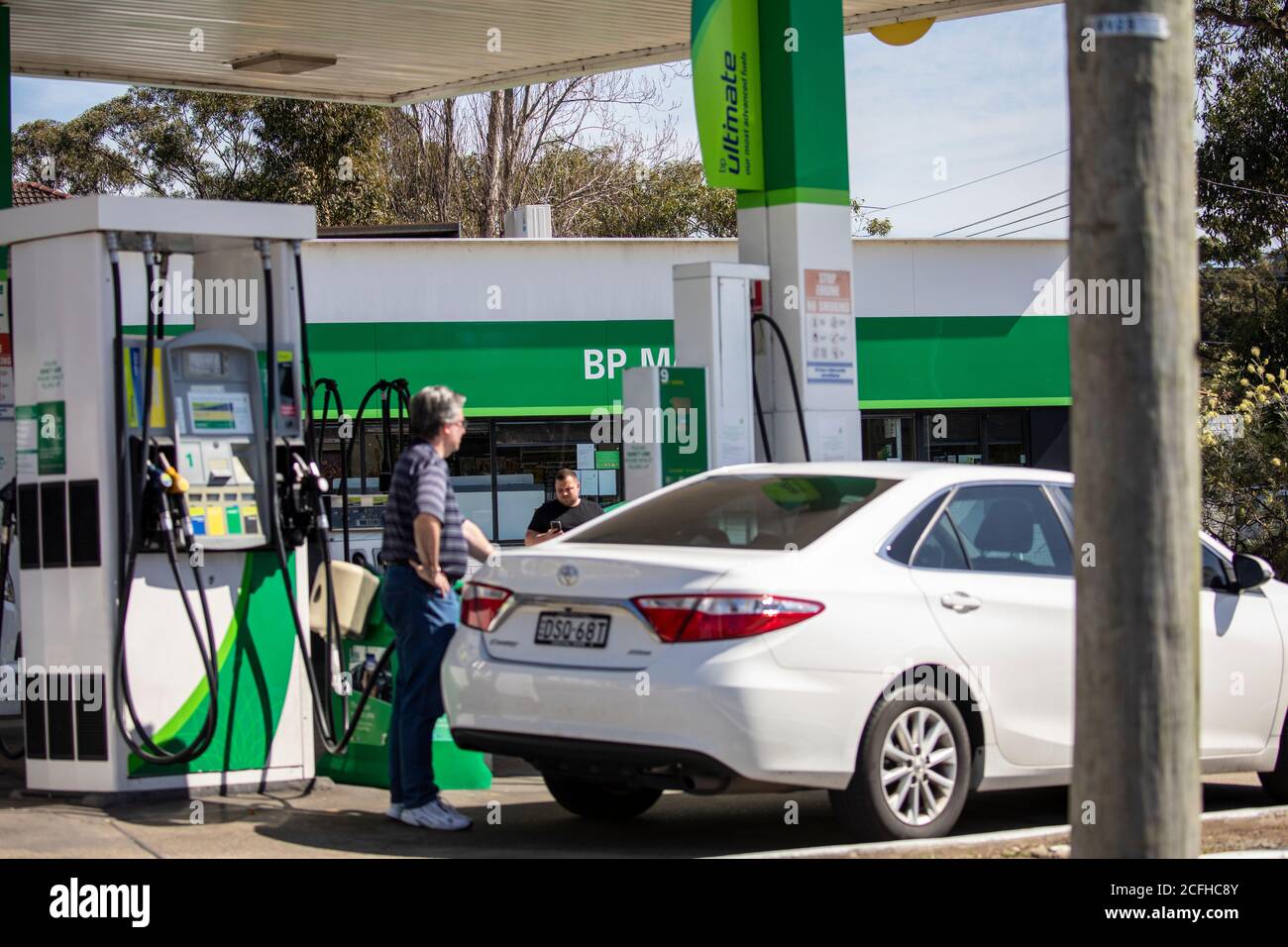 Australian man at a BP petrol service station fills his car up with fuel gasoline,Sydney,Australia Stock Photo