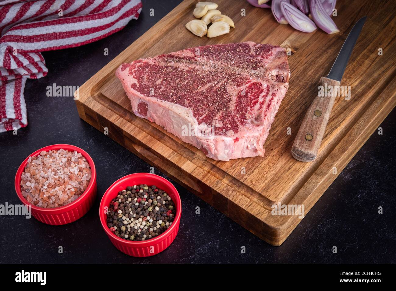 A photograph of a raw Porterhouse steak resting on a cutting board, coated with Himalayan sea
