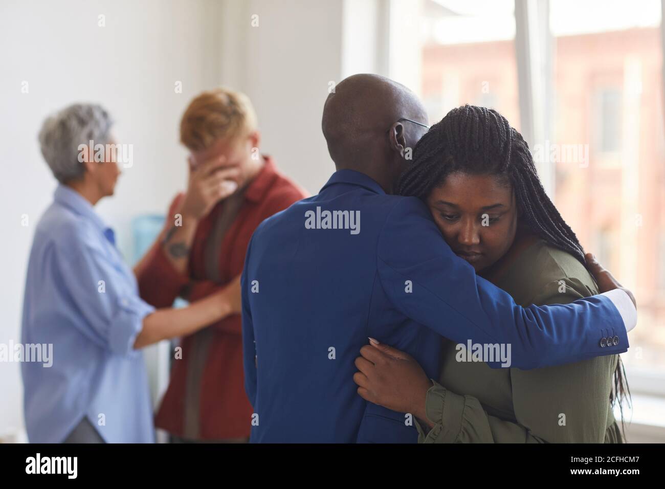 Waist up view at two African-American people embracing during support group meeting, helping each other with stress, anxiety and grief, copy space Stock Photo