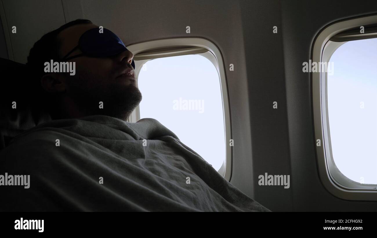 Rest and comfortable flight in the plane. Man in a mask for slee Stock Photo