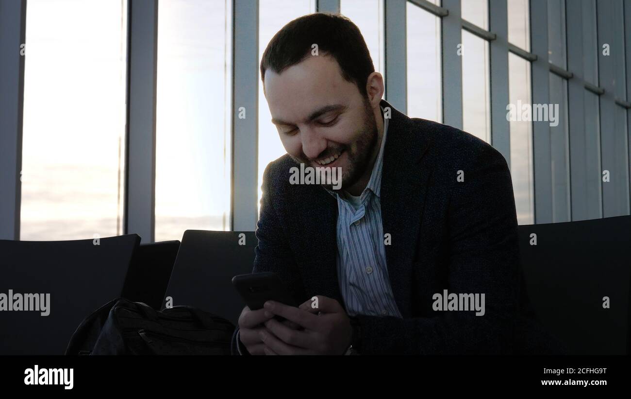 Elegant businessman looking at funny content on the phone sittin Stock Photo