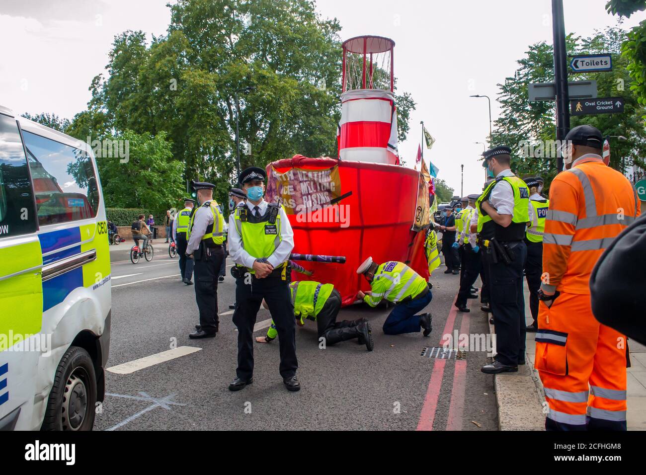 KENNINGTON, LONDON/ENGLAND - 5 September 2020: Man, woman and dog watching Extinction Rebellion's “Lightship Greta” boat being dismantled by police Stock Photo