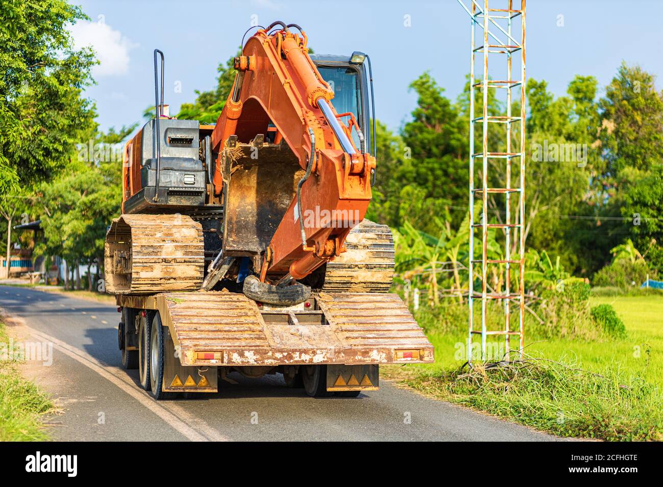 Backhoe excavator on truck on the road between transport Stock Photo