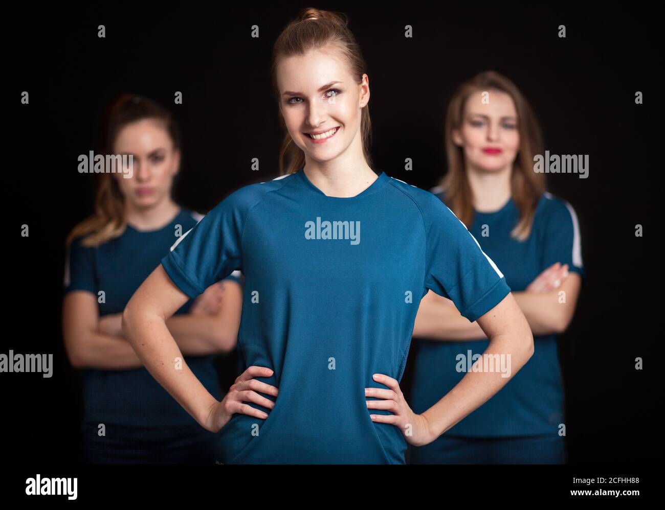 Team leader with two players of women football team on black background Stock Photo