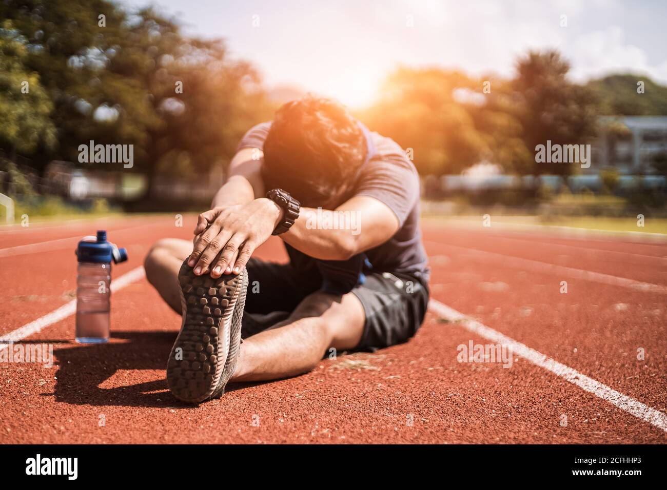 Full length portrait of a athletic man stretching at sport stadium. Stock Photo