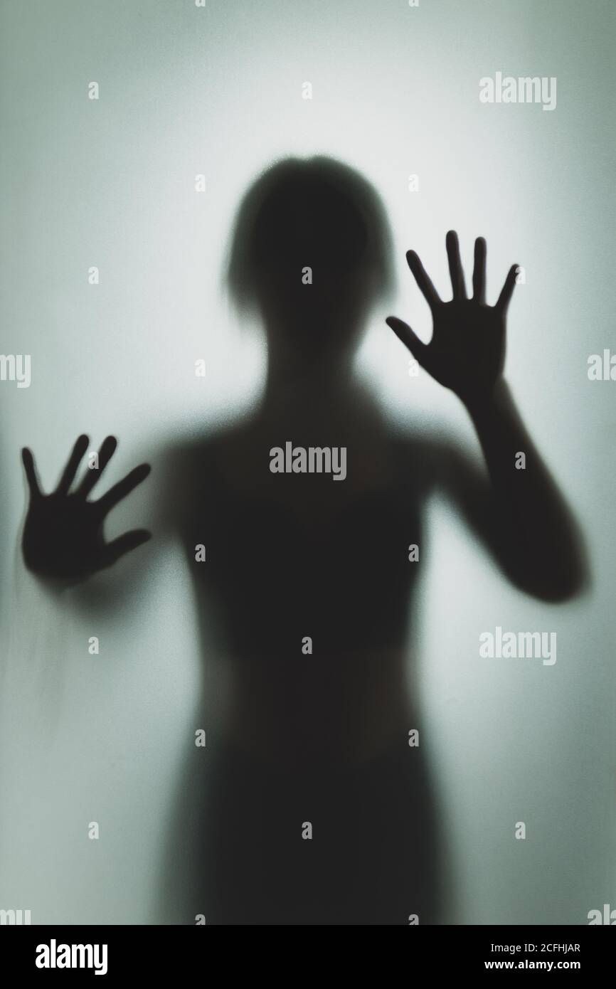 Ghost concept shadow of a woman behind the matte glass blurry hand and body soft focus Stock Photo