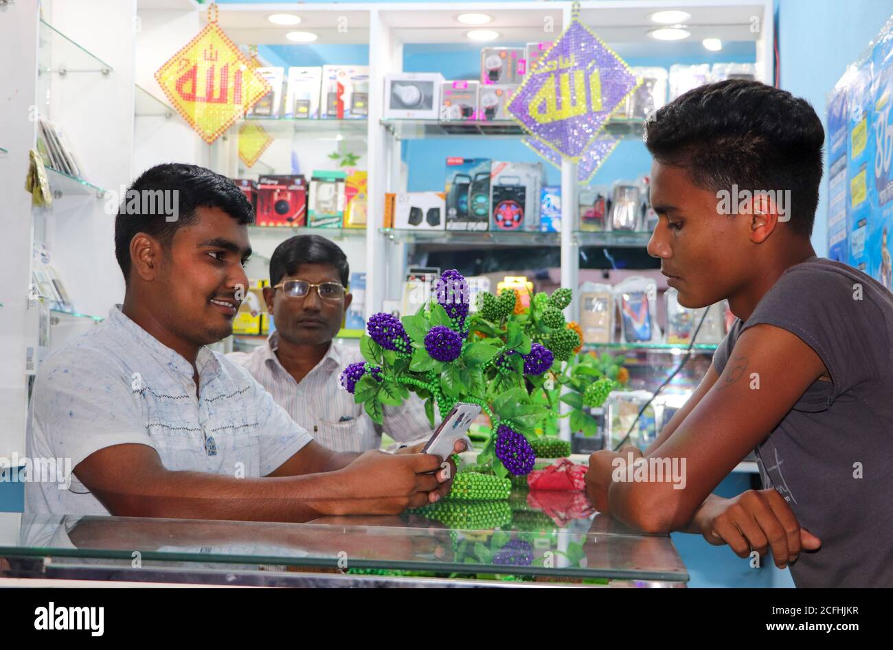 A retail seller showing a customer mobile phone, accessories for sale at a mobile shop of