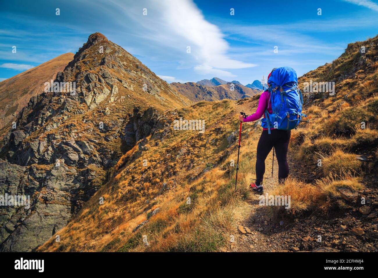 Cheerful hiker woman with backpack enjoying the view on the hiking trail, Fagaras mountains, hiking and travel concept, Carpathians, Romania, Europe Stock Photo