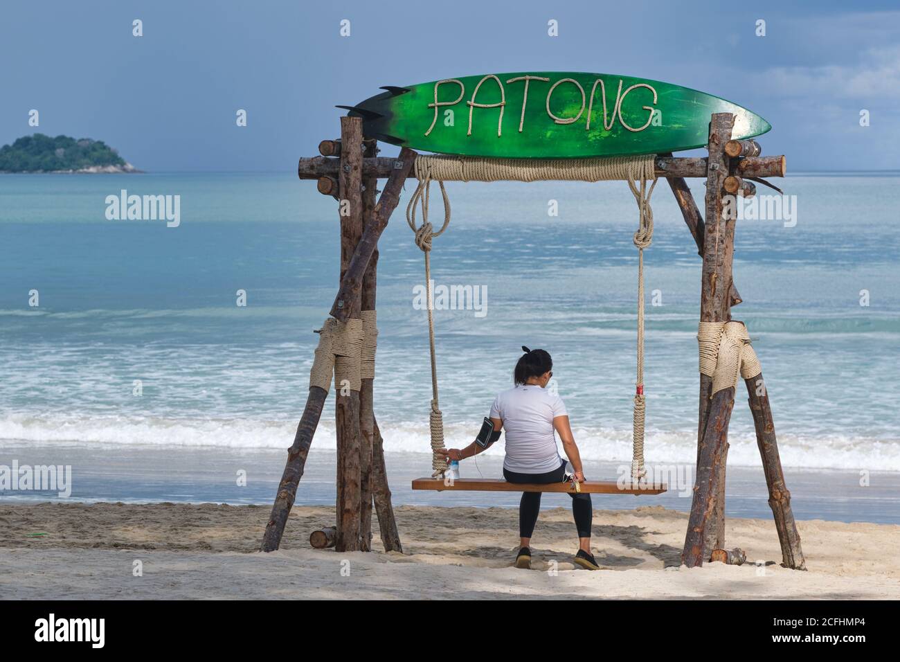 A female Thai sightseer in the times of Covid-19, relaxing on a swing on an otherwise empty Patong Beach, Phuket, Thailand Stock Photo