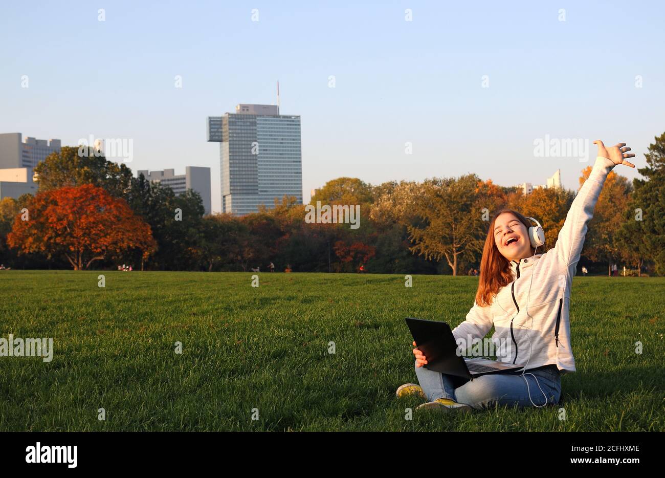 Unrecognizable teen girl sitting in meadow and drawing in