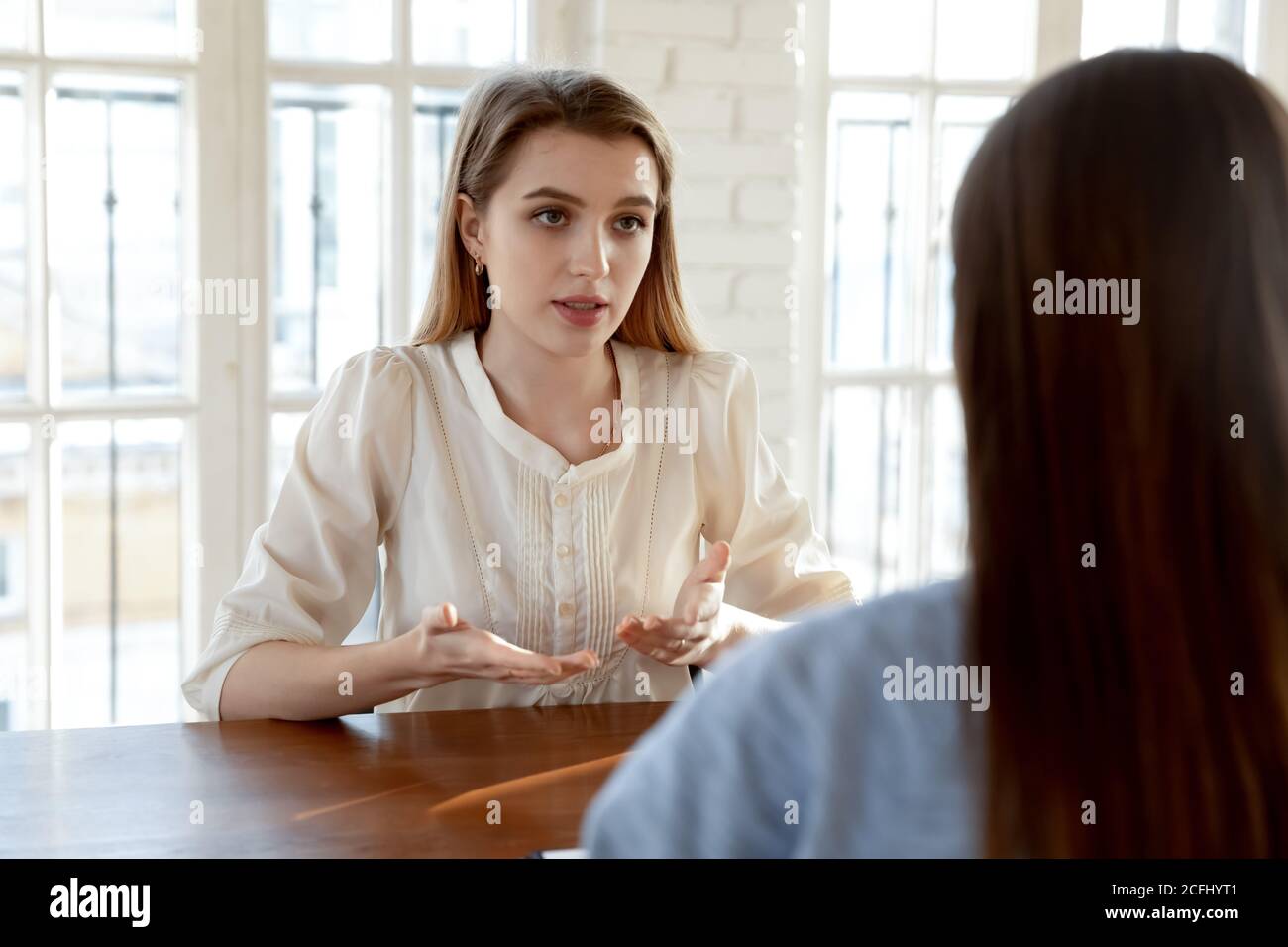 Confident young woman candidate answering employer questions at meeting Stock Photo