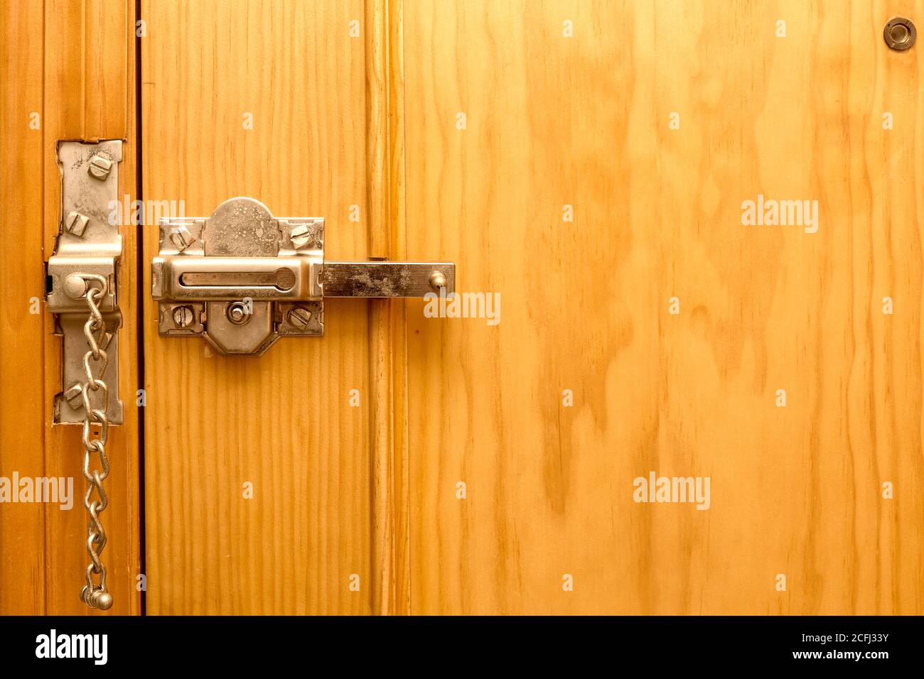 manual metal latch with chain on a wooden door Stock Photo