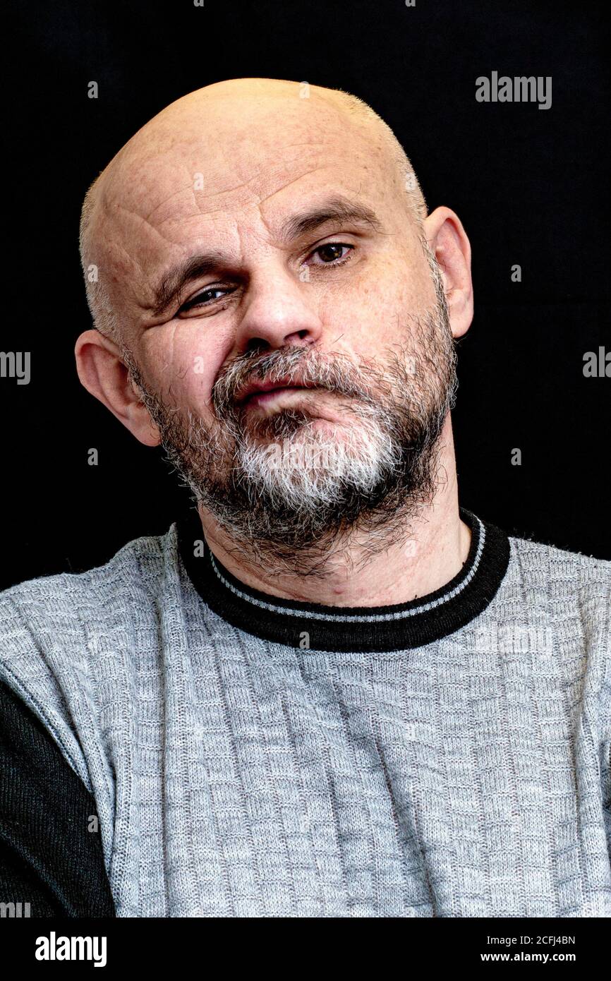 portrait of a middle-aged bald bearded man on a black background with a ...