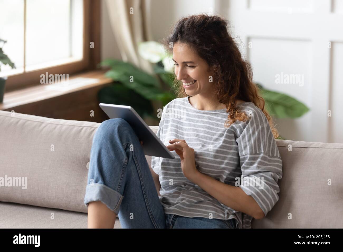 Woman sitting on sofa using tablet device buying on internet Stock Photo